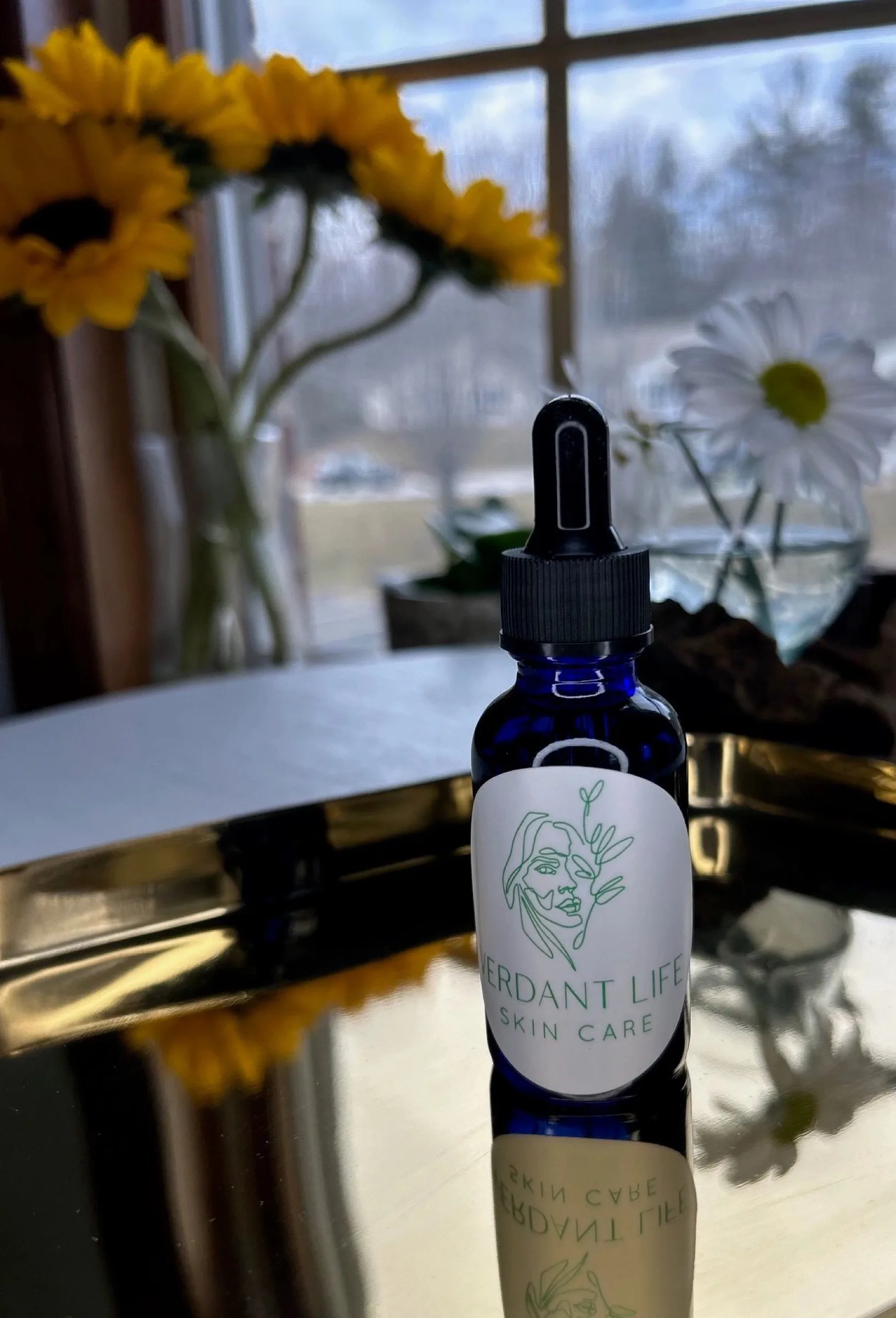 Blue glass dropper bottle of Verdant Life Lavender Oil on a gold tray.