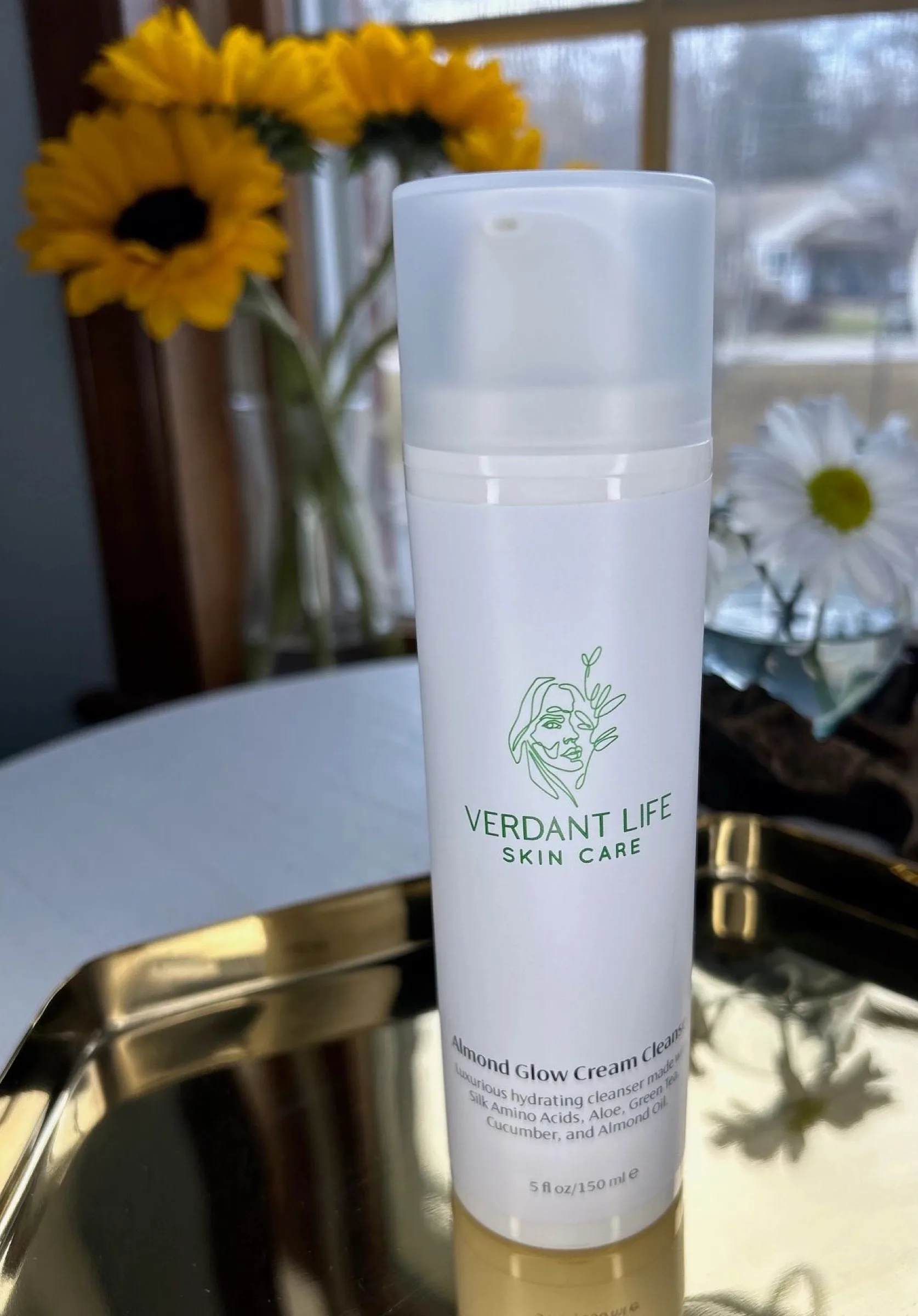 White pump bottle of Almond Glow Cream Cleanser on a gold tray.