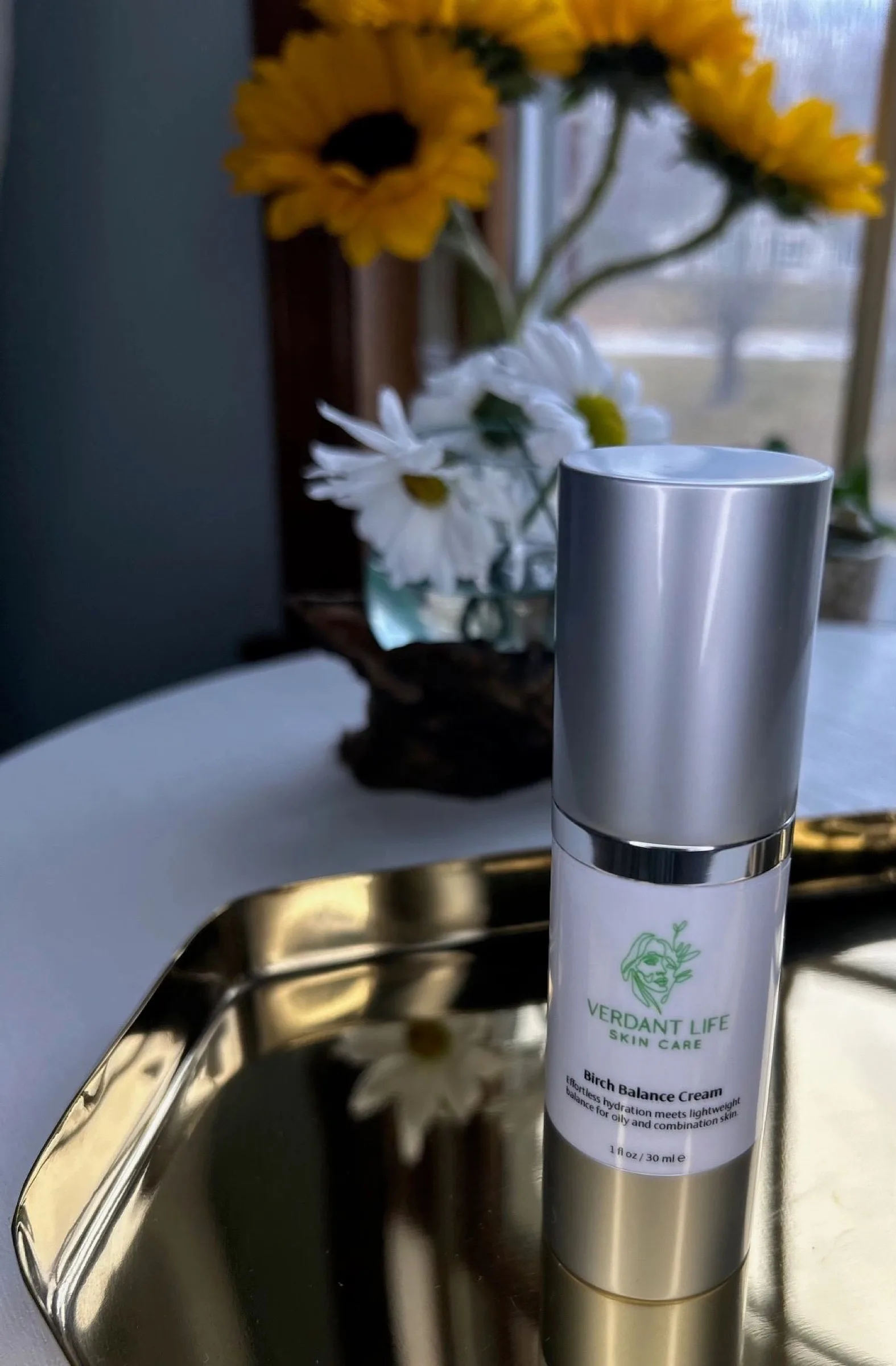 Silver-capped pump bottle of Birch Balance Cream on a gold tray.