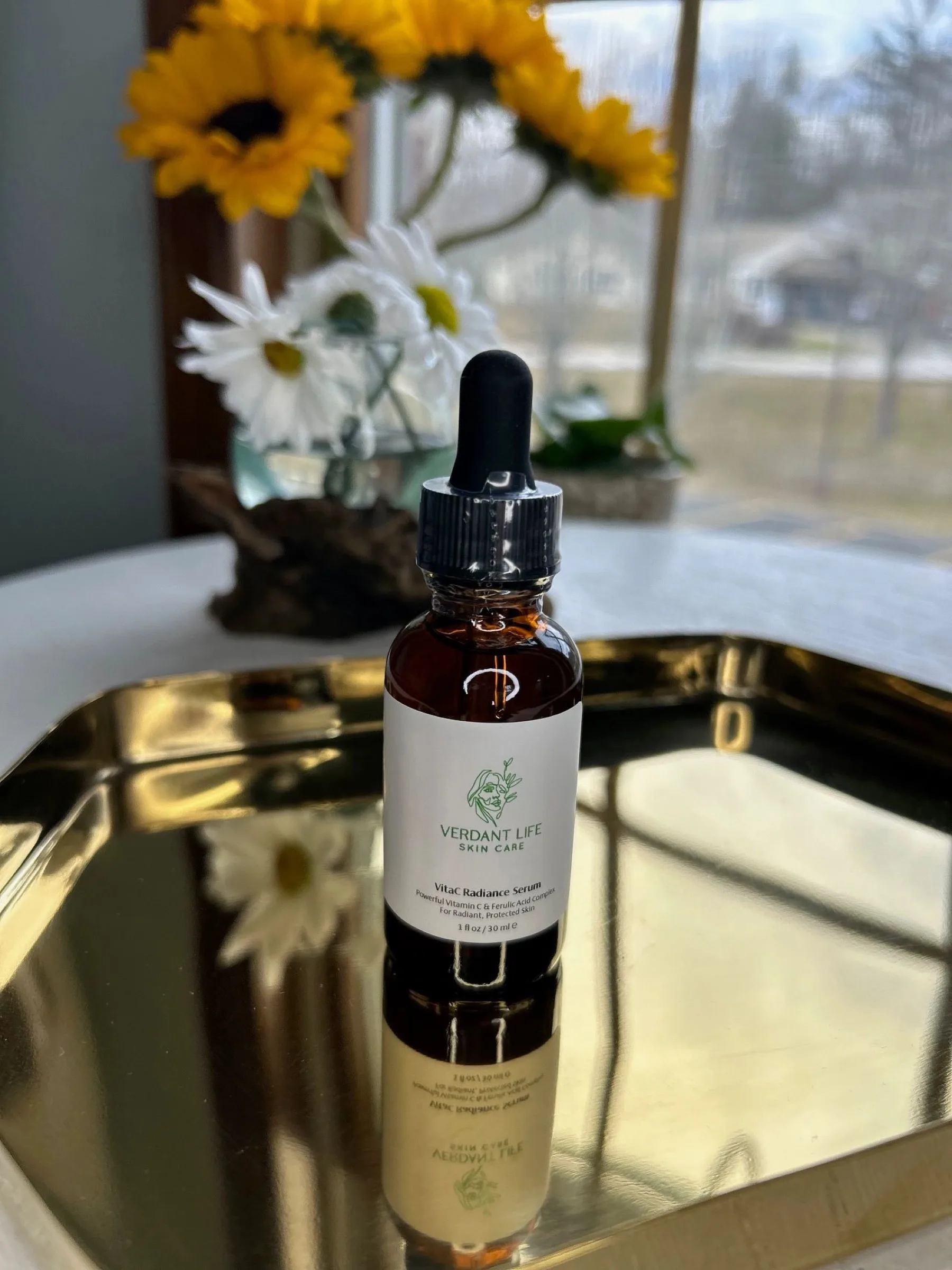 Amber glass dropper bottle of Vitac Radiance Serum on a gold tray.