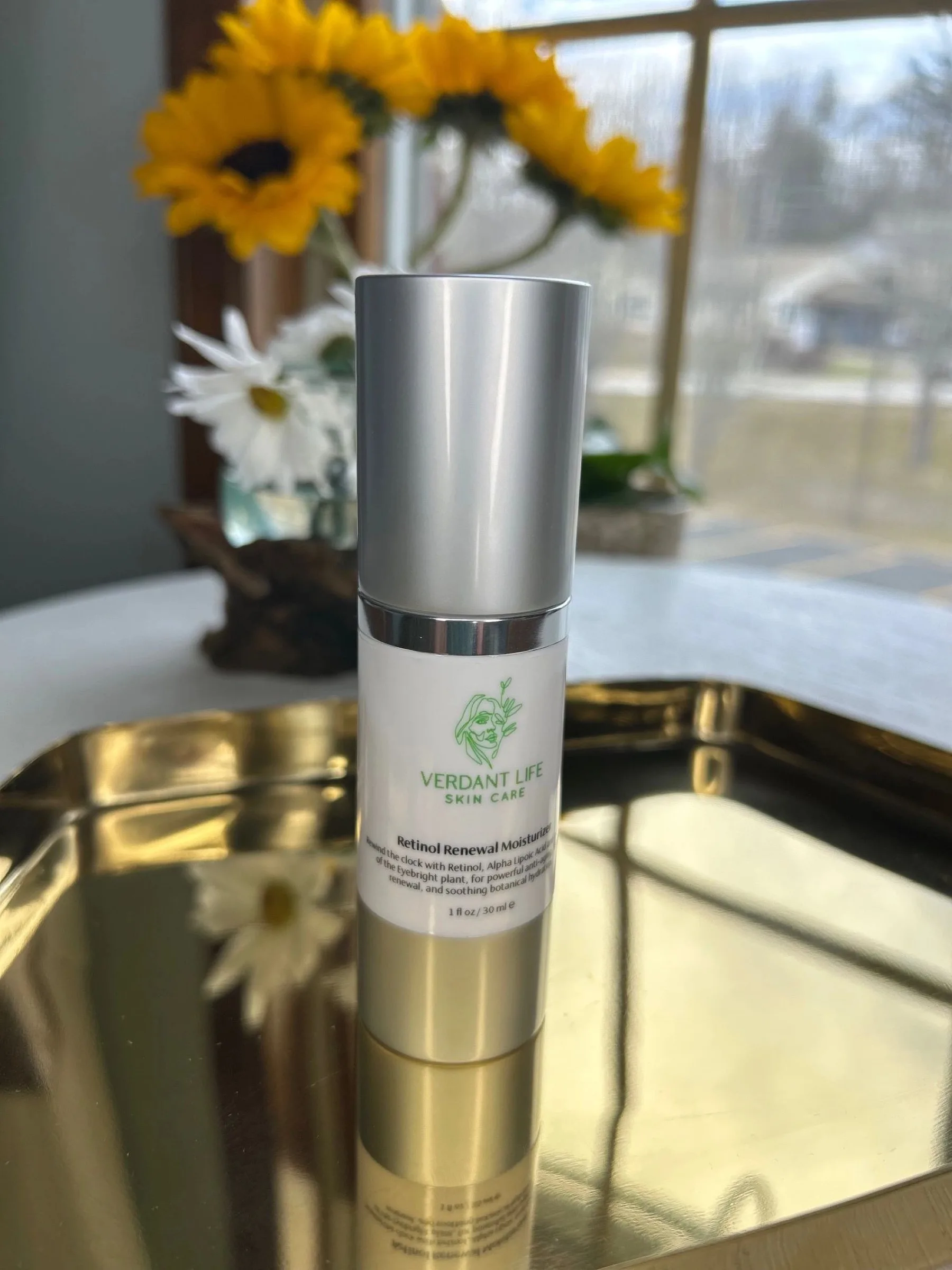 Silver-capped pump bottle of Retinol Renewal Moisturizer on a gold tray.