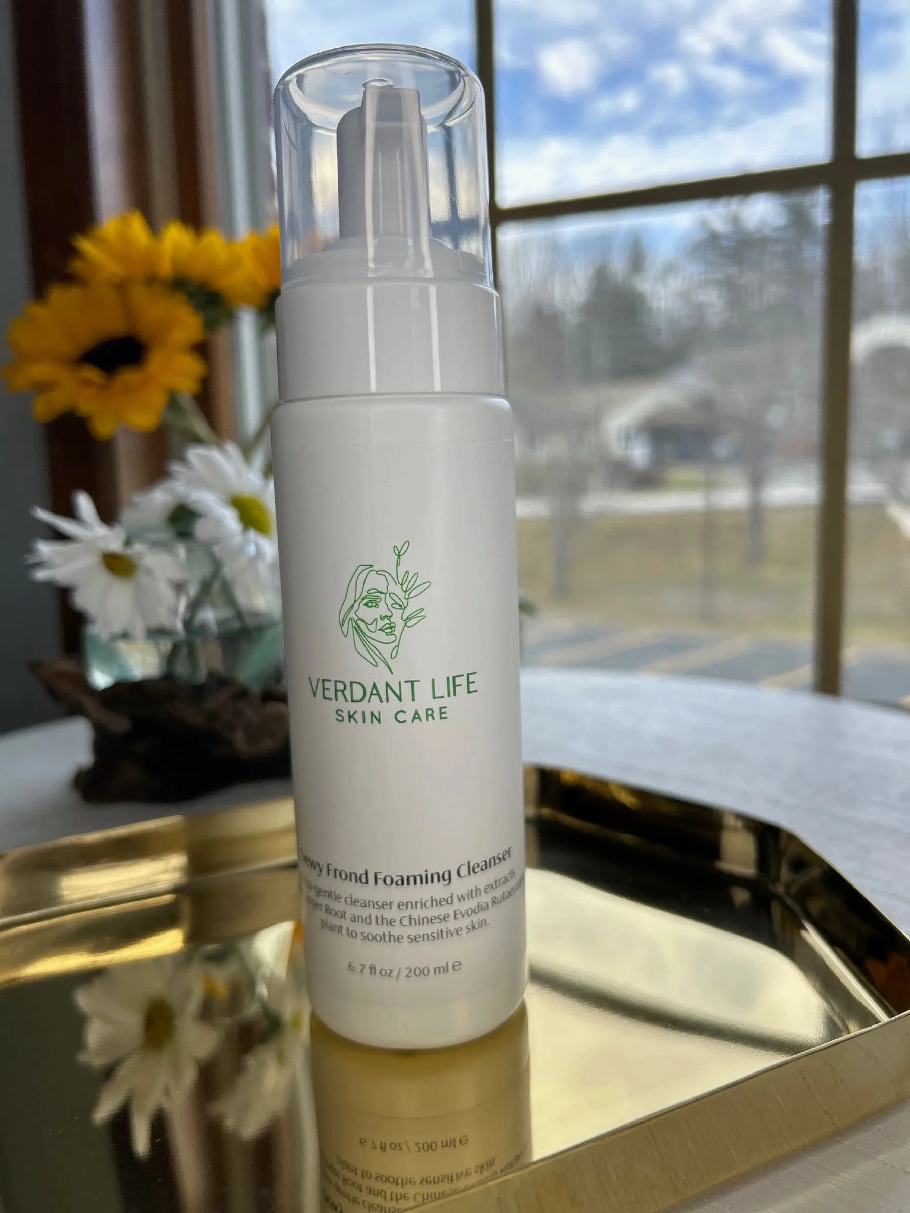 White foaming pump bottle of Dewy Frond Foaming Cleanser on a gold tray.