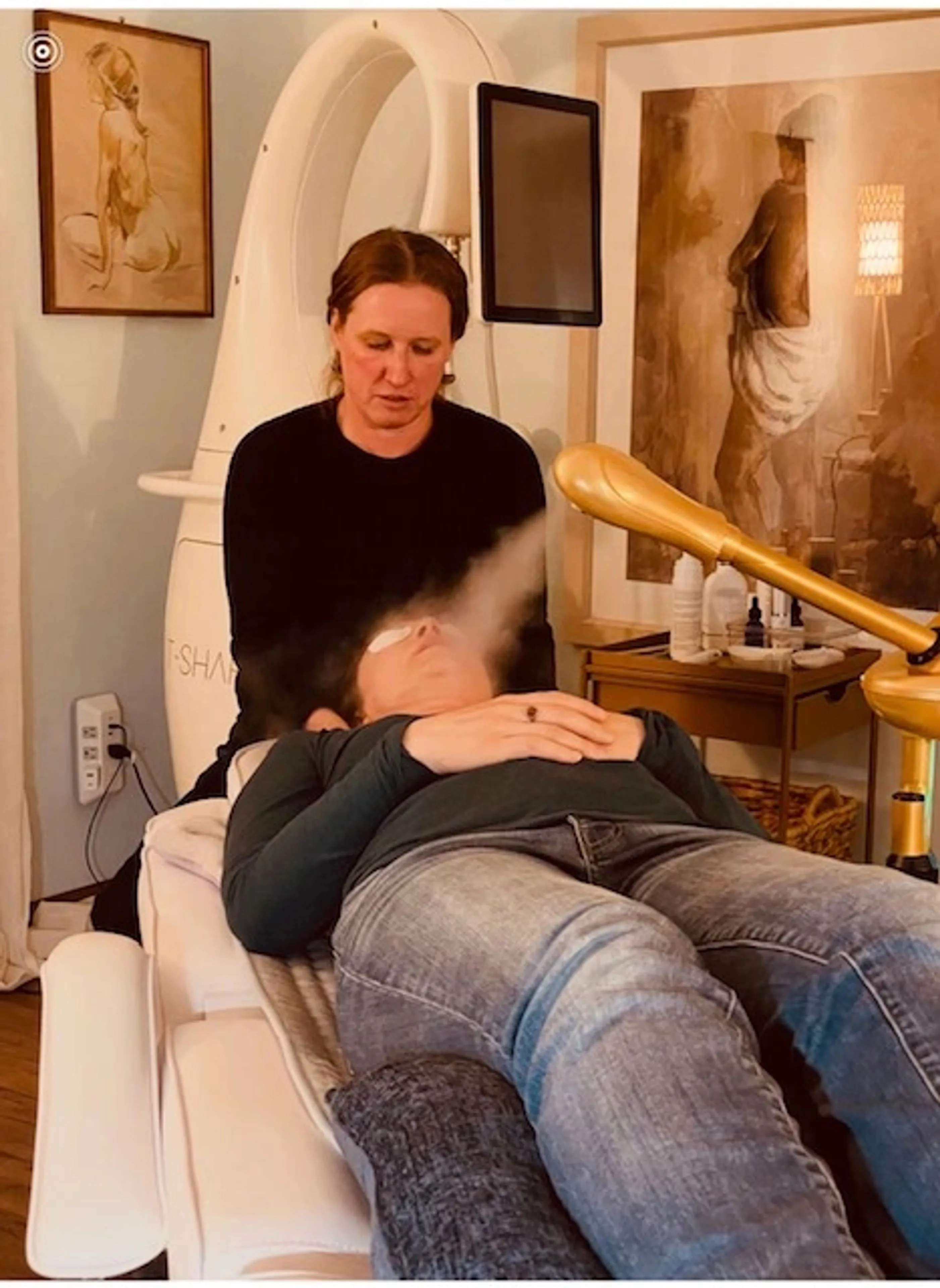 Dr Parrish steaming a client's face during a professional facial, the client reclining in a treatment chair