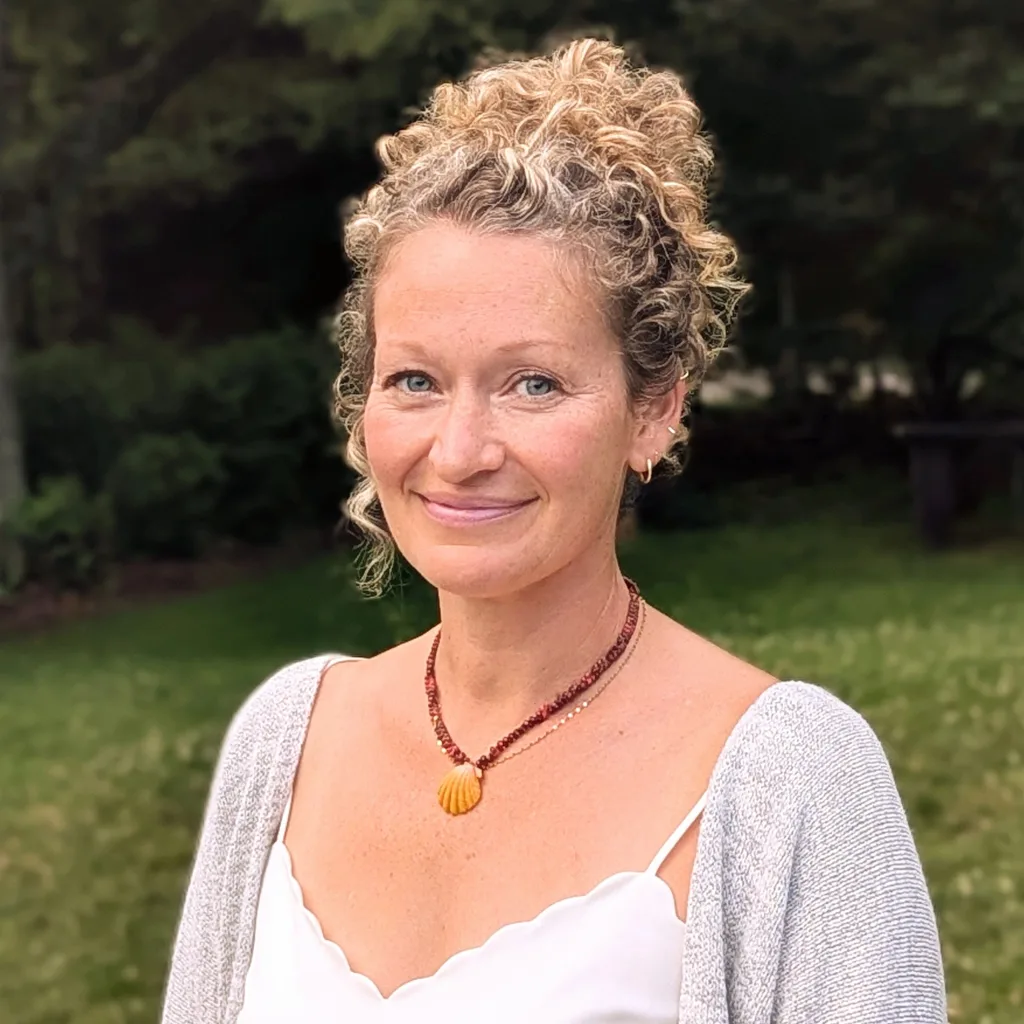 Mandy Morgan, licensed massage therapist, smiling outdoors with green trees behind her